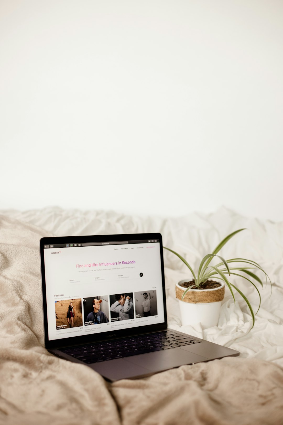 Apple laptop on a bed with influencer marketing platform on screen.